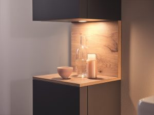 Wooden Qatego bathroom shelf and storage from duravit with downlighter shining on glass bottle and accessories