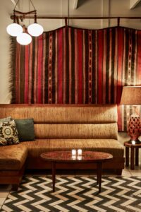 corner banquette with tiled pattern floor and moroccan carpet on the wall in The Moroccan Room by Studio Collective in The Bungalow