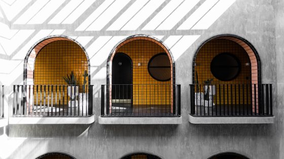 concrete wall with three arches through to bright yellow tiles at Casa Hoyos