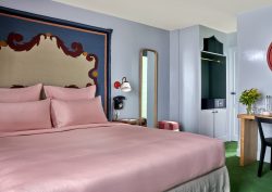 colourful guestroom at Hotel de la Boetie with pink bed linen blue patterned wall and green carpet