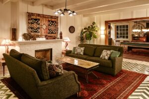 public area in hotel The bungalow with couches in front of central fireplace, tiled and carpeted floor