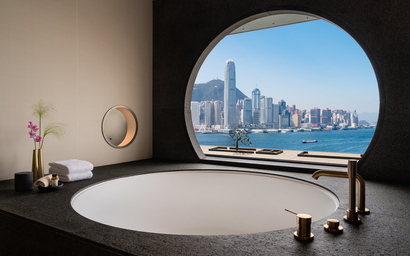 A circular window in hotel bathroom overlooking Hong Kong