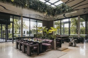 glass ceiling with planting above restaurant seating surrounded by windows looking out onto gardens