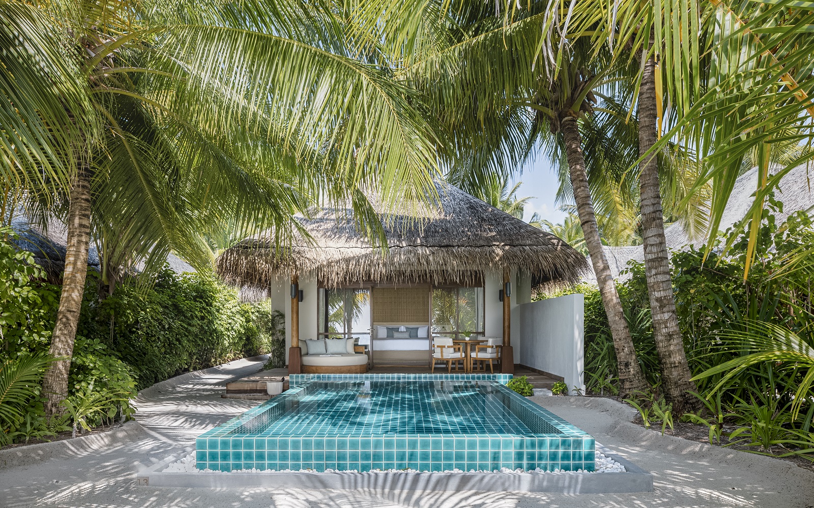 palm trees and plunge pool in front of beach cabin at Huvanfen Fushi by BLINK