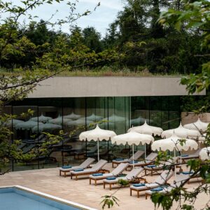 swimming pool and white umbrellas outside the spa with woodland in the background