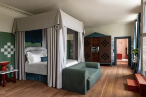 four poster bed with grey fabric and a couch at the end of a bed in period interior