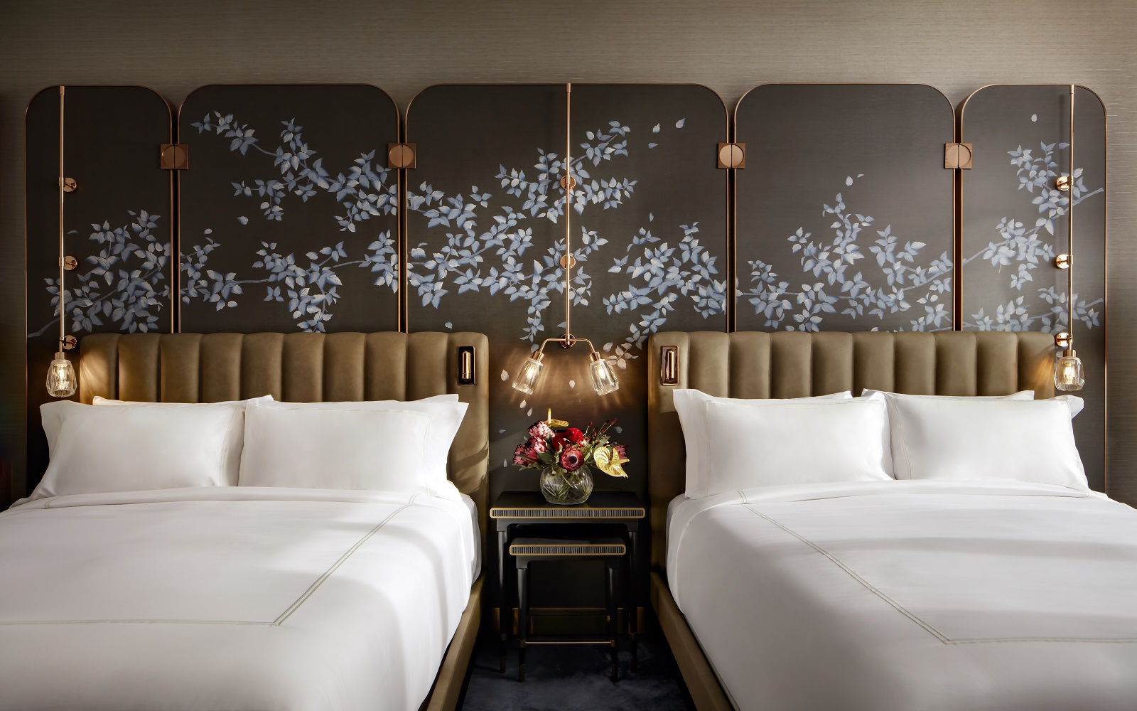 floral Asian inspired wall decoration behind double headboards with ceiling hung focussed lighting in guestroom at Raffles Boston