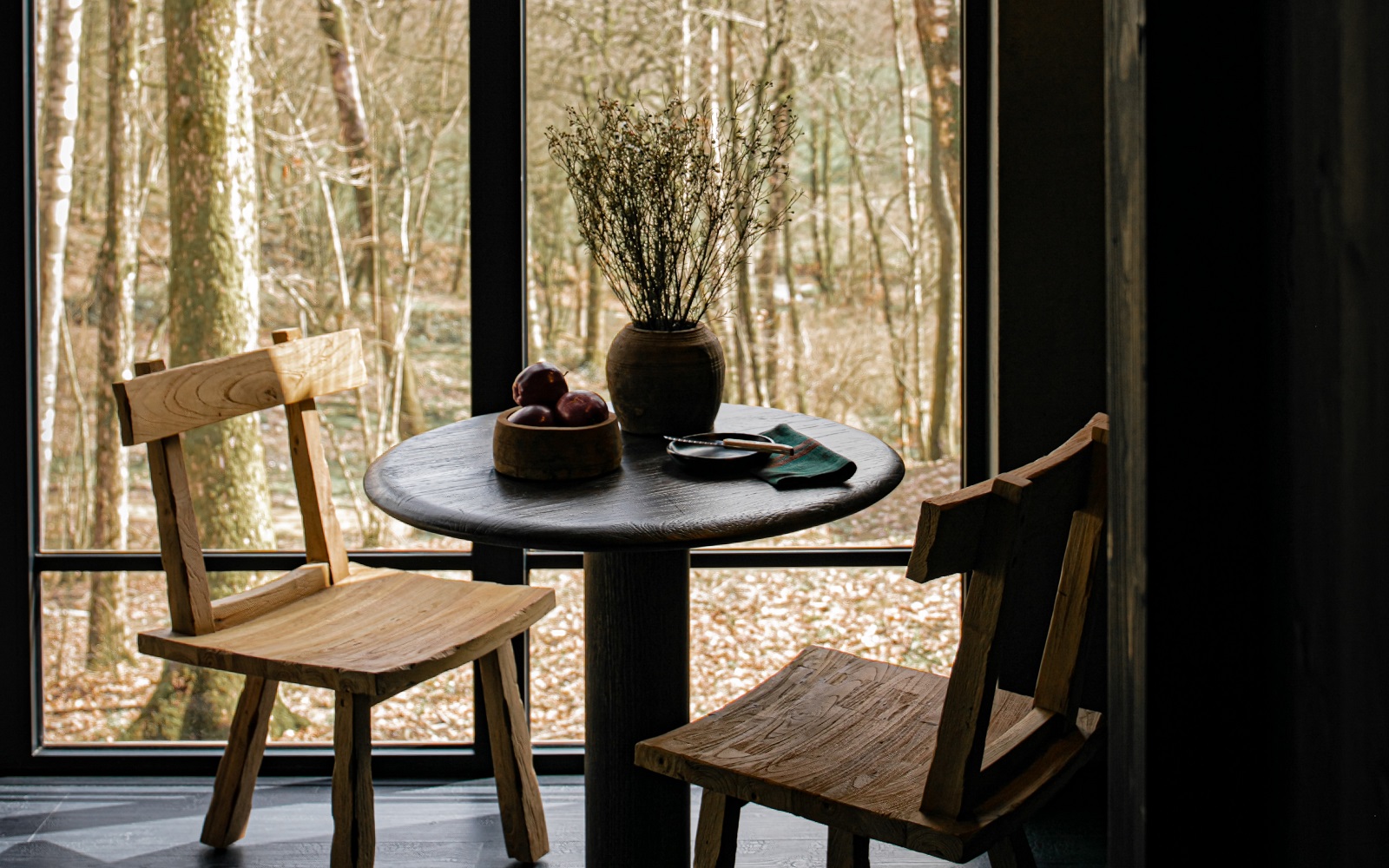 wooden table and chair in front of window looking out to woodland