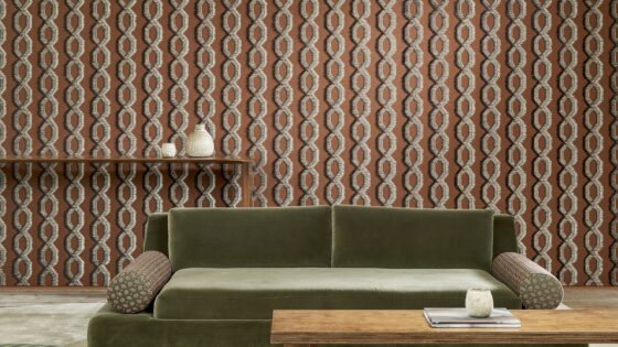 low green velvet couch and wooden coffee table in front of patterned Arte wallcovering from Le Couturier collection