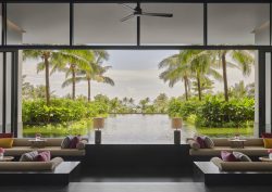 lounge in Regent Phu quoc with windows framing a view of palm trees and pool