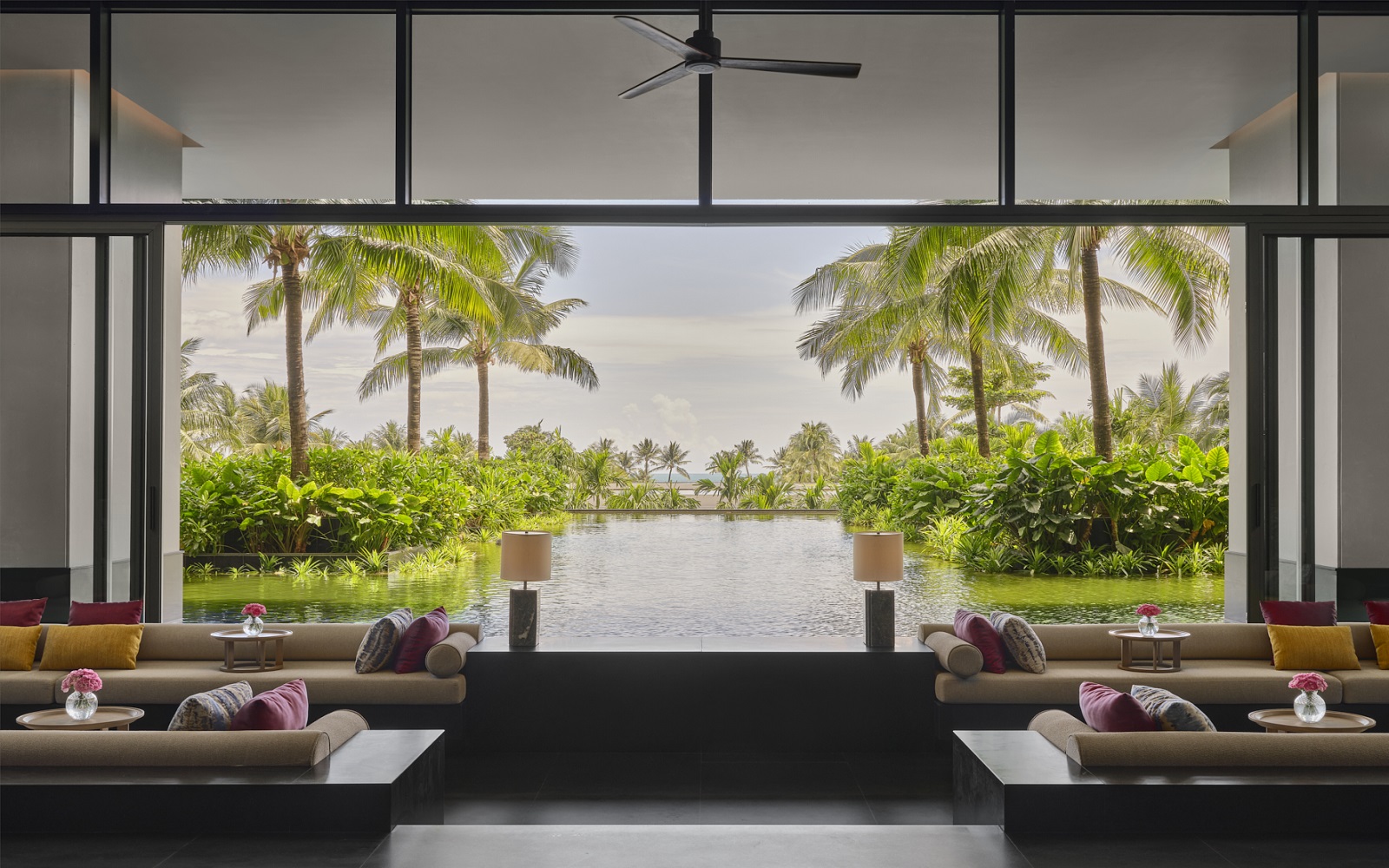 lounge in Regent Phu quoc with windows framing a view of palm trees and pool