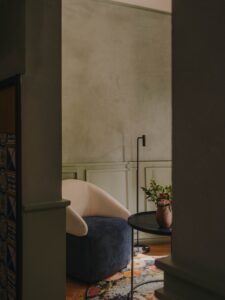 view through doorway to pink and blue seat and ceramic vase with flowers