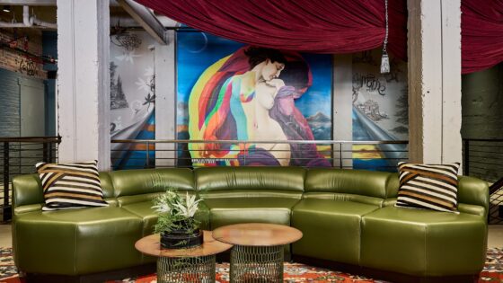 green curved sofa in front of graffiti style art in the lobby of The Radical