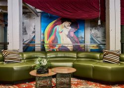 green curved sofa in front of graffiti style art in the lobby of The Radical