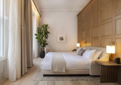 bed with white linen against a wooden panelled wall in guestroom at virgin Hotels Edinburgh